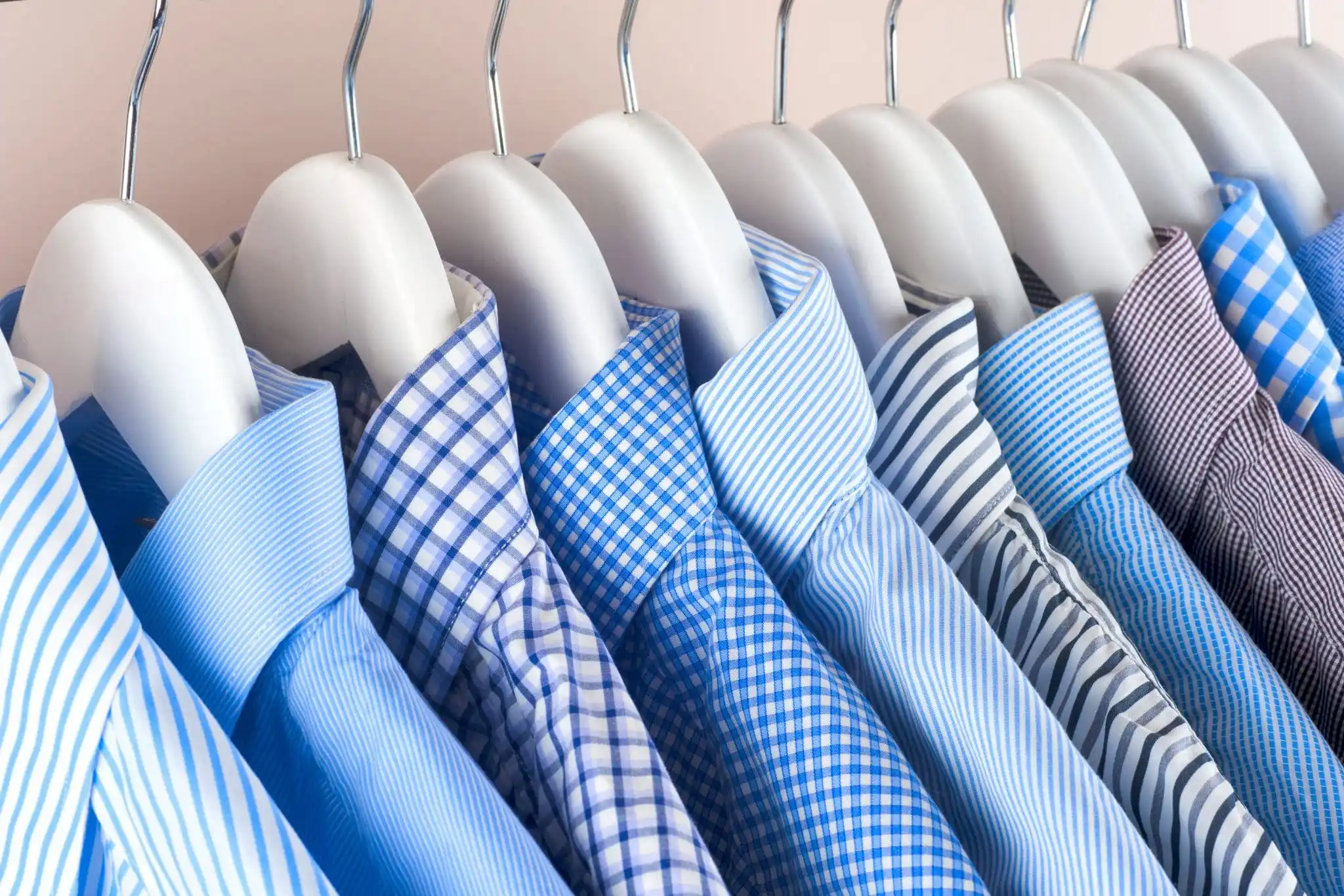 Collection of blue and white patterned dress shirts on hangers